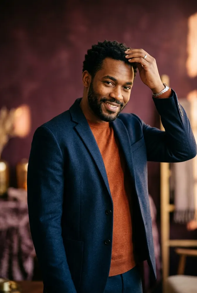 Homme afro aux cheveux courts crépus et à la barbe soignée, qui passe la main sur son front