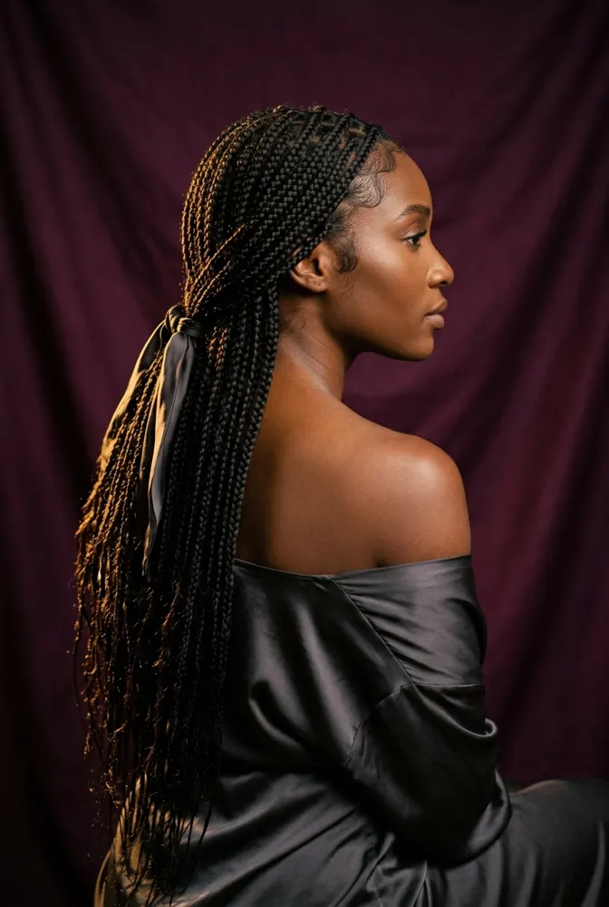 Femme afro de dos portant de longues tresses knotless lâches, contour naturel et détendu